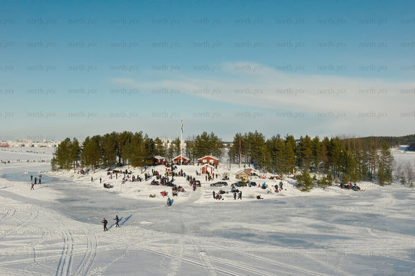 Snowy island park with people, cabins, and trees in Luleå city center during winter