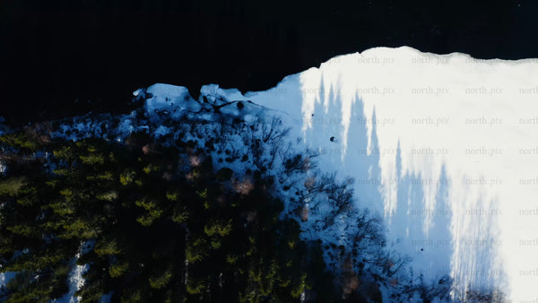 Winter in Luleå: Drone view of a partially frozen river and snowy forest