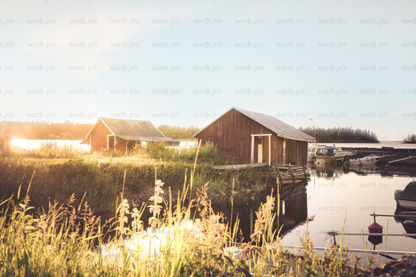 Boathouses and boats at waterfront during golden hour
