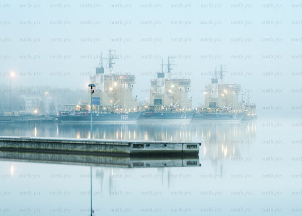 Three icebreaker ships docked in foggy harbor