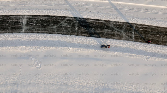 Aerial view of person pulling sled on frozen river in Luleå, on a sunny winter day