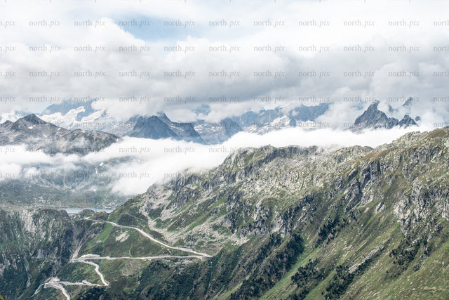 Winding mountain road through alpine ridges and clouds