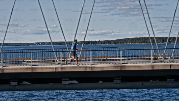 Man running across Bergnäsbron bridge in Luleå, on a sunny summer day