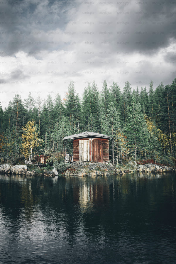 Wooden boathouse on a rocky lakeshore with pines