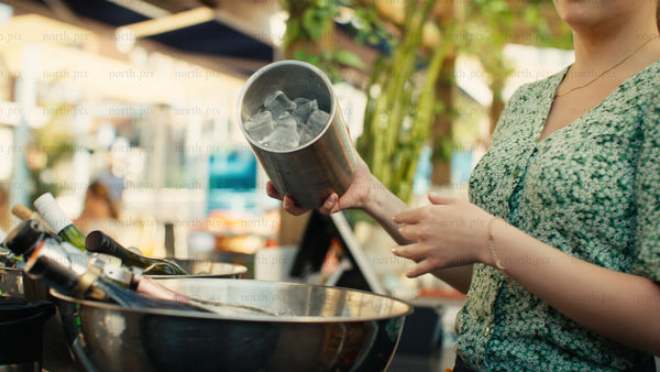 Bartender pours ice into a bucket at an outdoor bar on a sunny summer day in Luleå