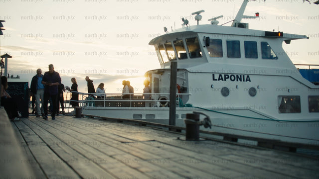 Urban summer evening: Passengers boarding tour boat at sunset in Luleå