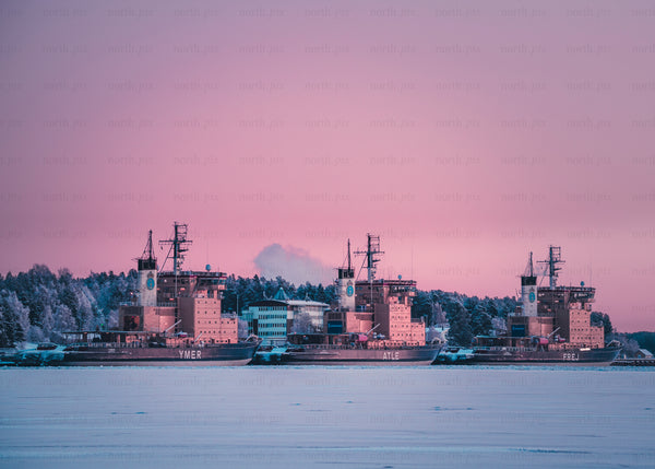 Three icebreaker ships docked at snowy harbor at sunrise in Luleå