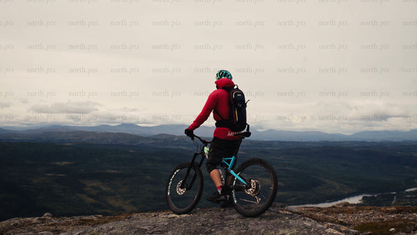 Mountain biker at summit before downhill ride - scenic valley view
