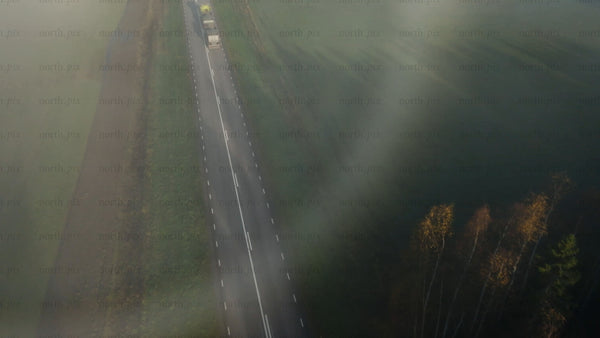Misty road through rural countryside with autumn forest and fields