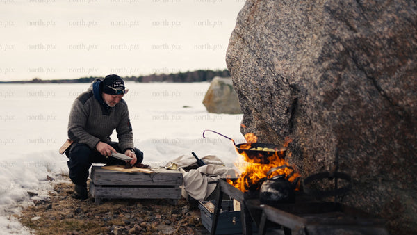 Man cooking on open fire, winter day in Luleå archipelago