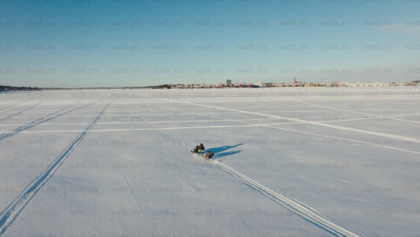 Snowmobile ride on frozen lake in Luleå - winter adventure with aerial drone footage of city skyline