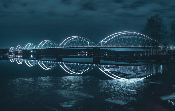 Lit arched bridge at night with reflection
