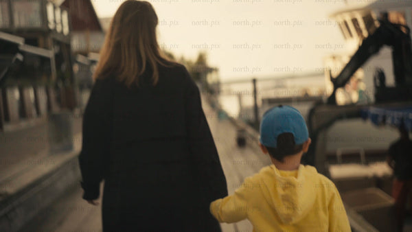 Mother and son walking down a pier in Luleå, at sunset during summer