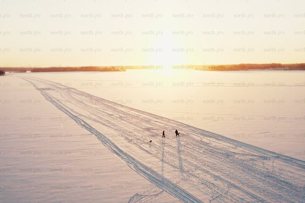 Sunset over snowy Luleå city center with tracks, people, and open winter horizon