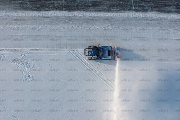 Snowplow clears snow on frozen water near Luleå city center — aerial winter cleanup