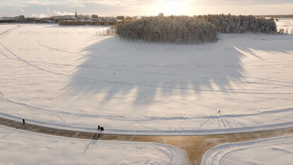 Winter wonderland in Luleå: Aerial view of snowy landscape with people strolling along path