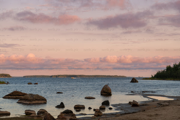 Rocky shoreline with islands and pink clouds at sunset