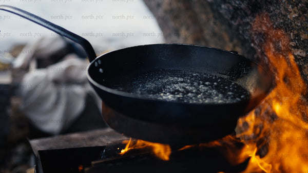 Melting butter in a frying pan over campfire in winter, Luleå
