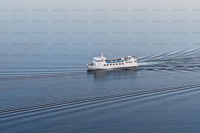 White ferry cruising through calm blue waters near Luleå city center on a clear day
