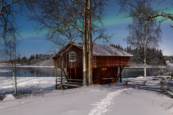Red boathouse by a frozen lake at night, winter
