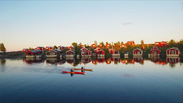 Kayaking in Luleå Archipelago at Sunset with Red Cabins: A Summer Drone View
