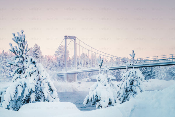 Snow-covered suspension bridge over a winter river