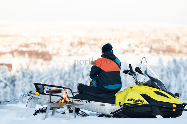 Person on snowmobile overlooking snowy forest in winter morning