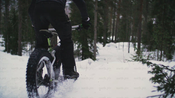 Fatbike riding through snowy forest trail in Luleå