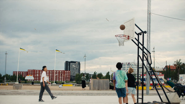 Friends playing basketball in Luleå on a cloudy summer day