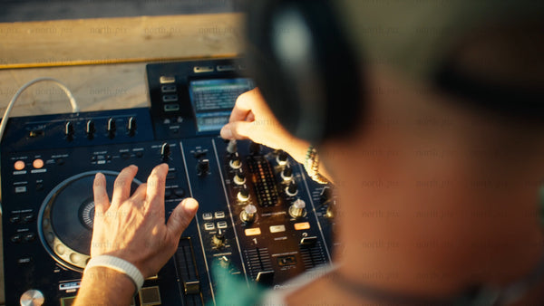 DJ mixing music at outdoor summer festival during golden hour