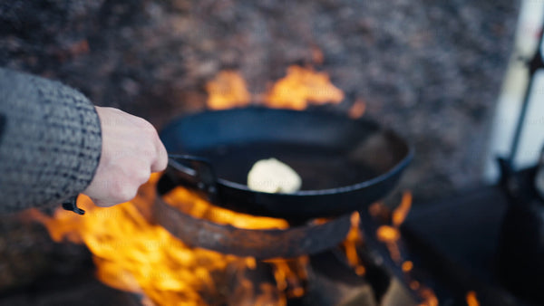 Melting butter in a cast iron pan over an open fire in winter, Luleå