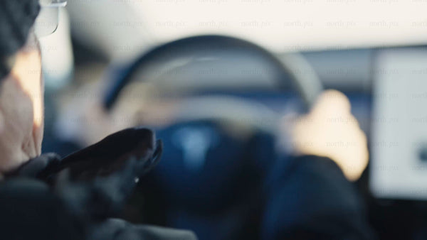 Man driving Tesla/car in Luleå on a bright winter day
