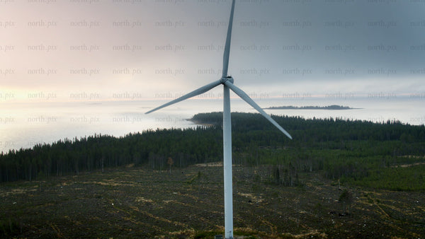 Rotating wind turbine: Clean energy generation against coastal sunset and cloudy sky