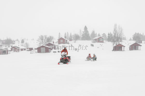 Snowmobile towing sled across frozen lake in winter