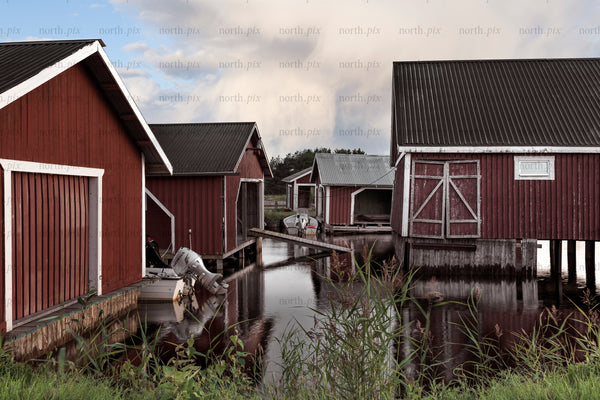 Red boathouses on piers in summer evening