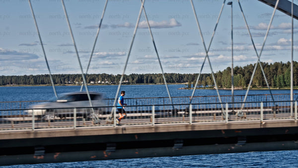 Man jogging across Bergnäsbron bridge in Luleå, on a sunny summer day