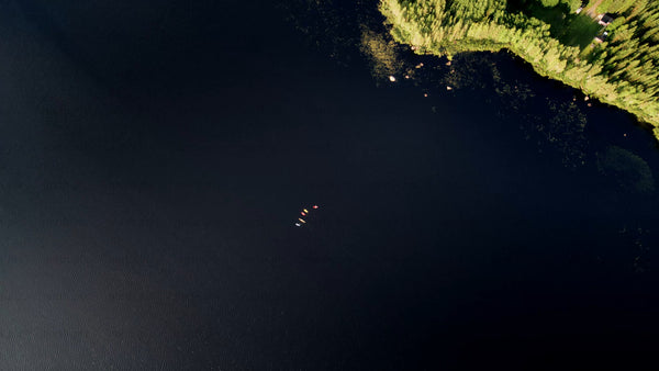 Kayakers on calm lake in Luleå, summer evening aerial view