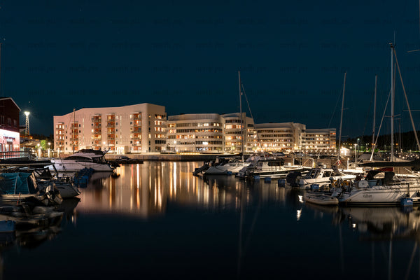 Night marina with moored boats and waterfront apartments