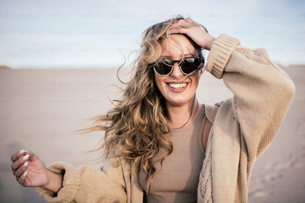 Woman wearing sunglasses on sandy beach in daylight