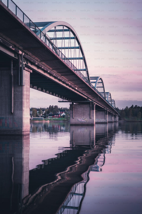 Arch bridge over river at dusk with reflection