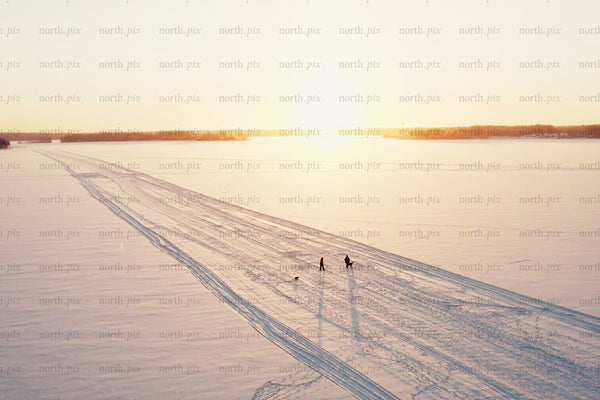 Sunset over snowy Luleå city center with tracks, people, and open winter horizon