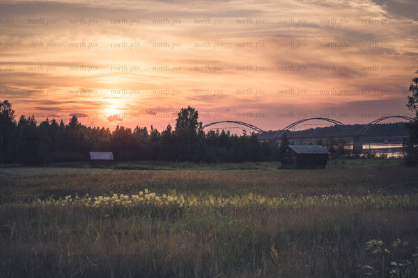 Sunset over meadow with gäddvik bridge and wooden huts