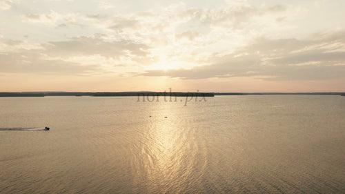 Solnedgång över lugn sjö med vattenskoter och kajaker i Luleå, Sverige