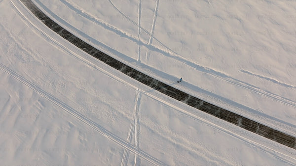Aerial view of person walking dog on snowy road in winter landscape, Luleå