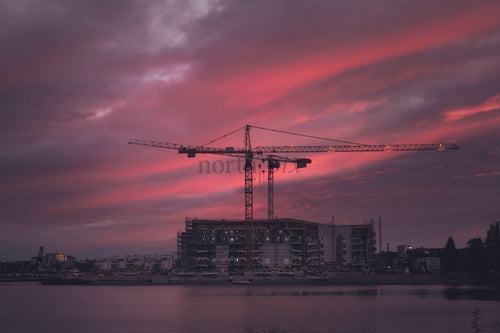 Construction cranes over waterfront building at dusk