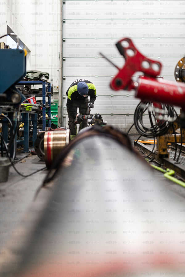 Worker repairing hydraulic pipe in industrial workshop