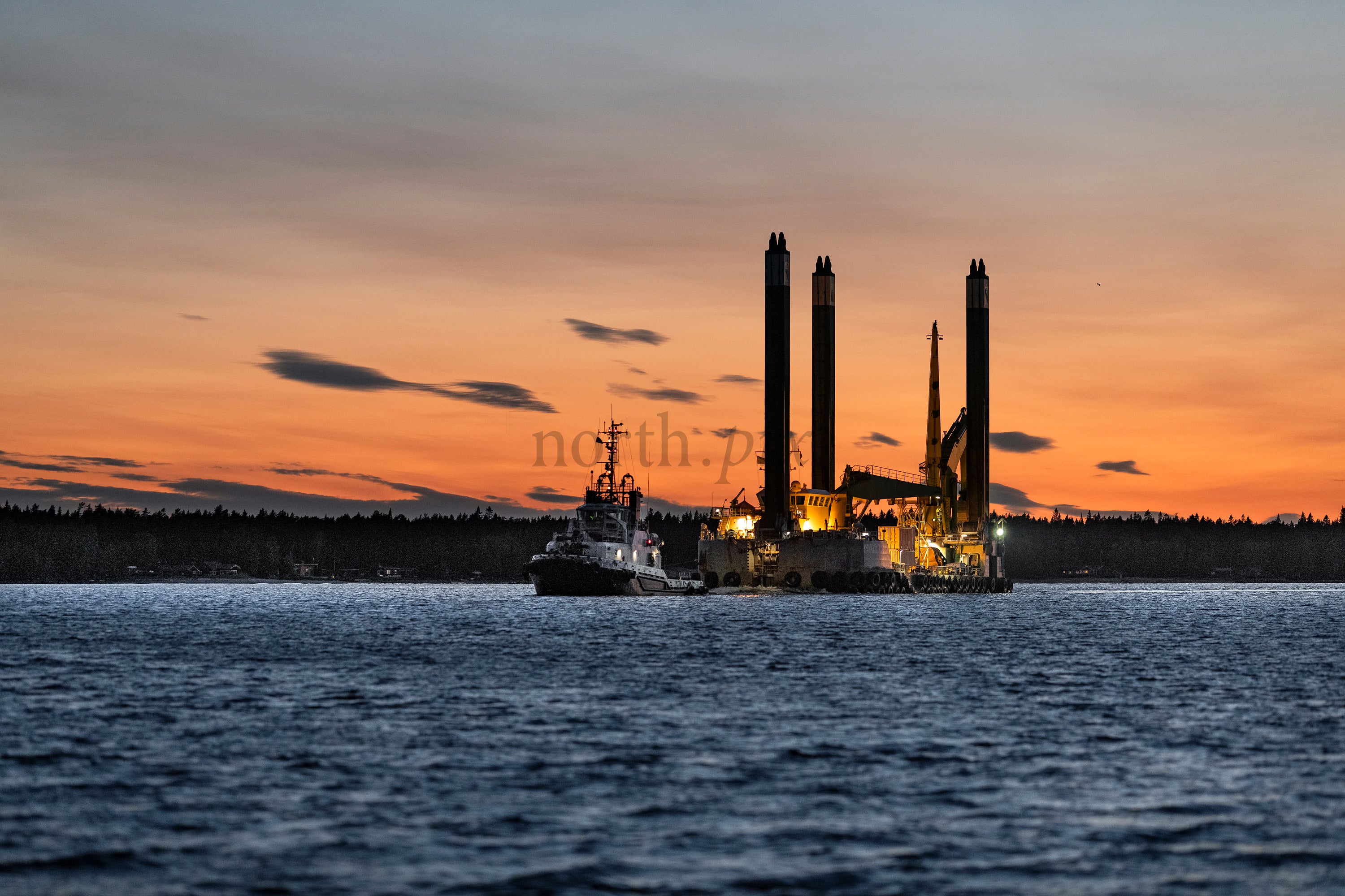 Work barge and tugboat at sunset over water