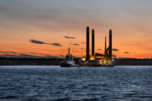 Work barge and tugboat at sunset over water