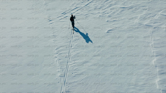 Skier crosses snowy mountain on sunny winter day