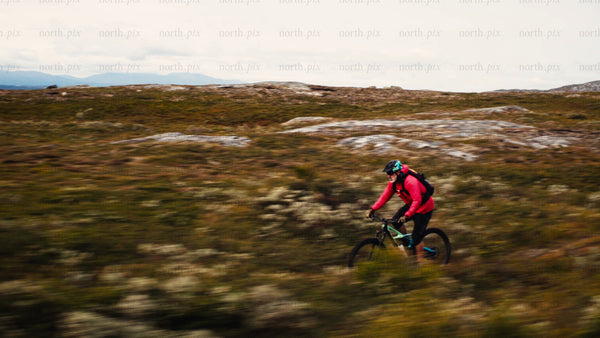 Man in red jacket on mountain bike rides downhill trail
